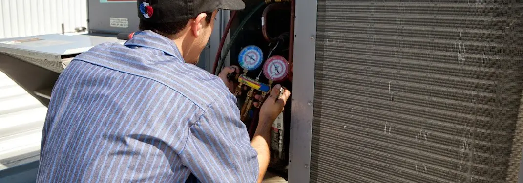 HVAC technician servicing a condenser unit in Orion